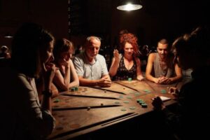 Spectateurs autour des tables de jeu de £¥€$ d’Ontroerend Goed